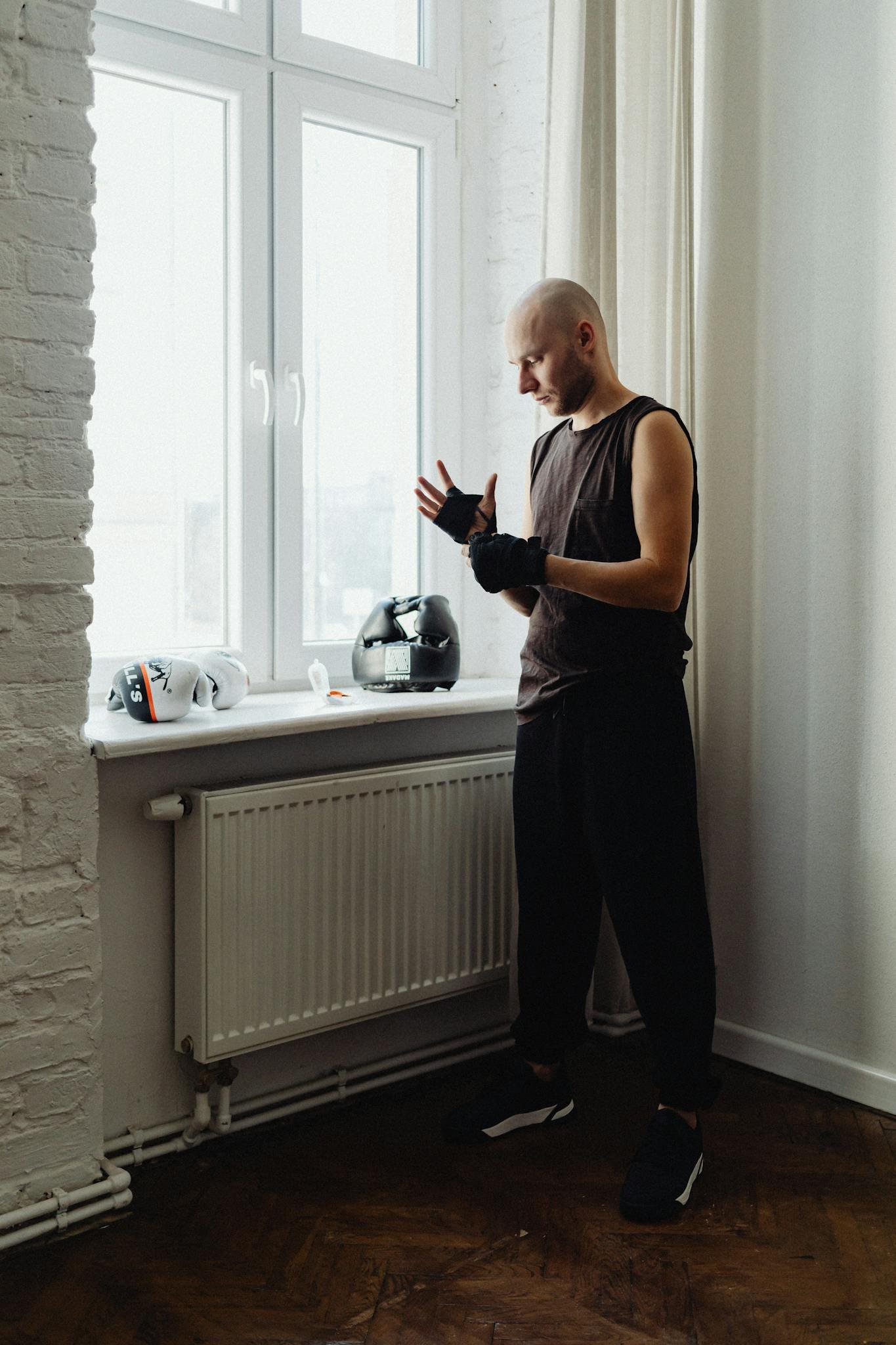Man wrapping hands before workout in a brightly lit indoor setting.